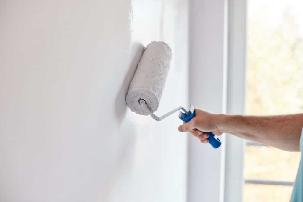 Man painting the inside of his home an off-white color